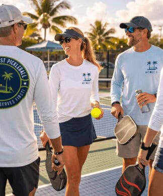 Pickleball players wearing Southernmost Pickleball logo shirts on a sunny outdoor court.