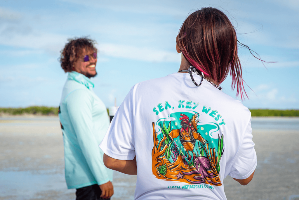 Two people standing on the beach wearing t - shirts.