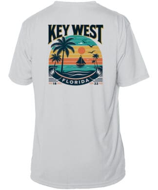 UPF 50+ Key West sun shirt with tropical sunset design, palm trees, and sailboat. Perfect for beach.