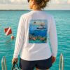 Woman in a white Key West Sun Shirts long sleeve with the Key West Snorkeling reef design on the back, on a boat over turquoise water
