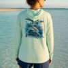 Woman on a Key West sandbar wearing the seagrass Key West Sun Shirts Sea Turtles UPF 50+ hooded sun shirt, turtle design across the back