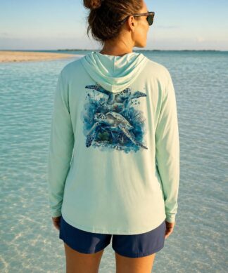 Woman on a Key West sandbar wearing the seagrass Key West Sun Shirts Sea Turtles UPF 50+ hooded sun shirt, turtle design across the back